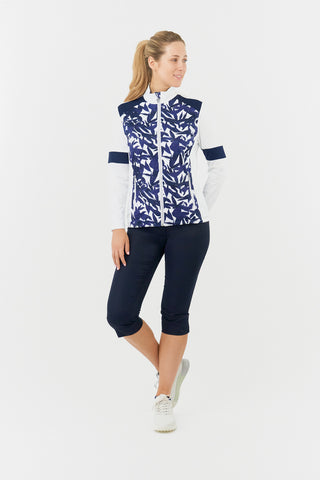 The Pure Golf Galena model shot features the mid layer jacket in Wild Peony: a botanical print in navy and white on the body and inside neck, complemented by white arms, a navy band around the elbow and block navy across the shoulders. 4-way stretch for comfort and a flattering fit on all body types. Designed to be anti-crease, anti-static, and quick drying, it also provides UPF 50+ protection. Made from 95% Polyester and 5% Spandex.