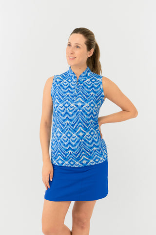 The Pure Golf Rise Santorini Skies sleeveless ladies' golf polo shirt  features a mesmerizing Ikat-inspired design in blues and white. With a regular fit and 4-way stretch, it ensures comfort and a flattering shape for all body types. The mandarin collar adds a touch of elegance. Crafted from 95% polyester and 5% spandex, it offers anti-crease, anti-static, and quick-dry properties, along with UPF 50+ sun protection. It is paired with our Royal Blue Skort. 