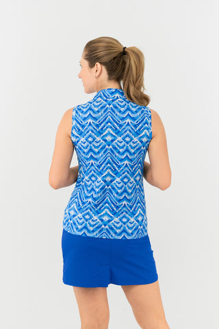 The back view of the Pure Golf Rise Santorini Skies Sleeveless Ladies' Golf Polo Shirt showcases a captivating Ikat-inspired design in shades of blue and white. Featuring a regular fit and 4-way stretch, it provides comfort and a flattering silhouette for all body types. The mandarin collar adds a touch of elegance. Made from 95% polyester and 5% spandex, the polo offers anti-crease, anti-static, and quick-dry benefits, along with UPF 50+ sun protection. It is paired with our Royal Blue Skort.