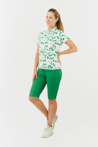 The Pure Golf Amity full model side shot of the short sleeve ladies golf polo shirt with botanical print in emerald green and white. Paired with Emerald Bermuda shorts. The polo shirt is a regular fit and has a 4 way stretch which ensures it is comfortable and flattering for all body types. It boasts a traditional collar for a classic and stylish look. The polo shirt is anti-crease, anti-static and quick dry with UPF 50+ which is and is 95% Polyester and 5% Spandex. 