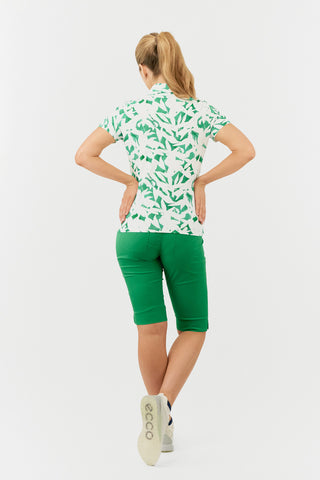 The Pure Golf Amity model shot  showing the back of the short sleeve ladies golf polo shirt with botanical print in emerald green and white. The polo shirt is a regular fit and has a 4 way stretch which ensures it is comfortable and flattering for all body types. It boasts a traditional collar for a classic and stylish look. The polo shirt is anti-crease, anti-static and quick dry with UPF 50+ which is 95% Polyester and 5% Spandex. 