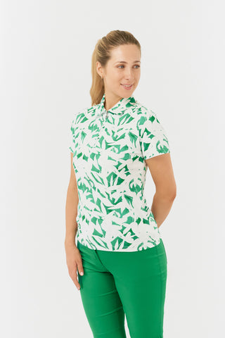 The Pure Golf Amity model half shot showing the short sleeve ladies golf polo shirt with botanical print in emerald green and white. The polo shirt is a regular fit and has a 4 way stretch which ensures it is comfortable and flattering for all body types. It boasts a traditional collar for a classic and stylish look. The polo shirt is anti-crease, anti-static and quick dry with UPF 50+ which is 95% Polyester and 5% Spandex. 