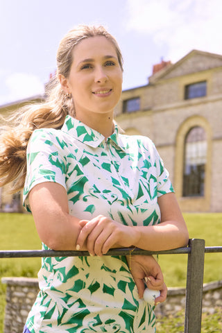 The Pure Golf Amity lifestyle front shot of the short sleeve ladies golf polo shirt with botanical print in emerald green and white. It is a regular fit and has a 4 way stretch which ensures it is comfortable and flattering for all body types. It boasts a traditional collar for a classic and stylish look. The polo shirt is anti-crease, anti-static and quick dry with UPF 50+ which s 95% Polyester and 5% Spandex. 