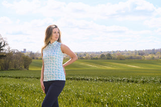 The Pure Golf Amity lifestyle shot highlights the Amity Short Sleeve Ladies' Golf Polo Shirt in Floating Palms White, featuring a bold all-over botanical print in Ocean Colour against a fresh white backdrop. This regular-fit polo offers 4-way stretch for comfort and a flattering fit on all body types. With its traditional collar, it delivers a timeless look. The shirt is designed to be anti-crease, anti-static, and quick-drying, while also offering UPF 50+ sun protection. 95% Polyester and 5% Spandex.