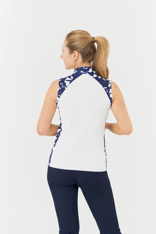 The Pure Golf Freda model shot highlights the sleeveless ladies' golf polo shirt, featuring a botanical print in navy and white across the shoulders, sides, and mandarin collar, with a white body. This regular-fit polo shirt provides a 4-way stretch for comfort and a flattering fit on all body types. Designed to be anti-crease, anti-static, and quick-drying, it also offers UPF 50+ protection. Made from 95% Polyester and 5% Spandex. 