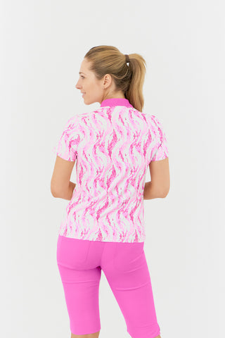 The Pure Golf Felicity short-sleeve ladies' polo shirt, captured from the back, highlights the delicate layers of pink and white feathers. Showcased with Azalea Pink Bermuda Shorts. Designed for a regular fit, it features a 4-way stretch for comfort and a flattering silhouette on all body types. The chic sweetheart collar enhances its fashionable appeal. Crafted from 95% Polyester and 5% Spandex, this polo is anti-crease, anti-static, and quick-drying, while also providing UPF 50+ sun protection