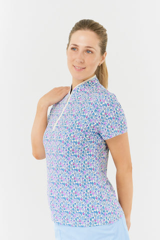 The back view of the Pure Golf Ellen short-sleeve ladies' polo shirt highlights our Over Eighteen Print, featuring cocktail motifs in a delicate scale. Designed with a regular fit, this polo provides a 4-way stretch for comfort and a flattering silhouette on all body types. The chic sweetheart collar adds a fashionable detail. Made from 95% Polyester and 5% Spandex, it offers anti-crease, anti-static, and quick-dry benefits, as well as UPF 50+ sun protection. It is paired with a light blue skort.