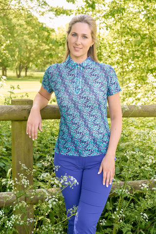 The Pure Golf Serendipity Mesh Short Sleeve Polo Shirt Lifestyle shot in Floating Palms-Yale, showcasing prints with a summery aquatic essence of multi-blue tones. The breathable mesh fabric, ensures optimal airflow, keeping you cool and comfortable on the course. Offering a 4-way stretch for comfort and a flattering shape on all body types. The stylish traditional collar adds a classic look. This polo is made from 95% Polyester and 5% Spandex, offering anti-crease, anti-static, and quick-dry properties. 