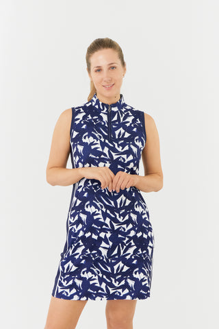 The Pure Golf model shot of the Heather Sleeveless dress highlights a botanical print in navy and white, accented by a flattering navy side panel. Crafted from 4-way stretch material for maximum flexibility and unrestricted movement, it also features detachable shorts for added versatility and coverage. The mock neck collar provides a sleek, modern look while ensuring a flattering fit for all body types. Designed to be anti-crease, anti-static, and quick-drying, it also offers UPF 50+.