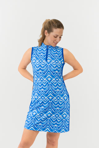 The Pure Golf model shot highlights the front of the Sophie Sleeveless dress, in our Santorini Skies print in shades of blue and white, complemented by a flattering Royal Blue side panel. Crafted from 4-way stretch fabric, it offers freedom of movement, with detachable shorts for added coverage. The mock neck collar adds a sleek touch, and the dress is designed to flatter all body types. Built to resist creasing, static, and moisture, providing UPF 50+ protection. Made from 95% Polyester and 5% Spandex. 