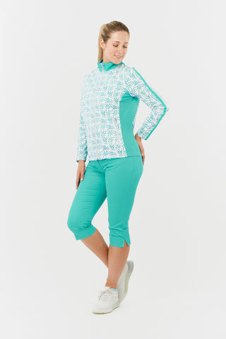 The model shot of the Pure Golf Gella Ladies Golf Mid Layer Jacket in Floating Palms White showcases a bold botanical print set against a clean white backdrop, with ocean block color accents on the mock neck, sides, and a thin stripe down each arm. This regular-fit polo offers 4-way stretch for a flattering fit on all body types. Made from 95% Polyester and 5% Spandex, the jacket is designed to be anti-crease, anti-static, and quick-drying, UPF 50+. Paired with Trust Capri's in Ocean. 