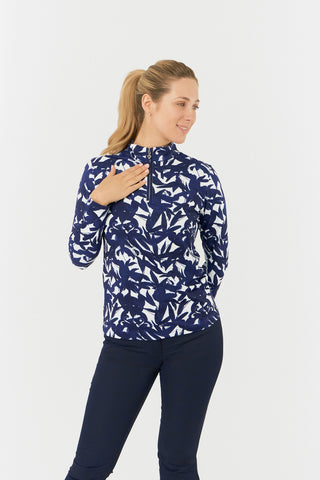 The Pure Golf Serenity long-sleeve ladies' golf zip top model shot showcasing a front view of our botanical print in Wild Peony Navy. Designed with a regular fit, it offers a 4-way stretch for comfort and a flattering shape on all body types. The mock neck collar offers a sleek, modern look and extra coverage. Made from 95% Polyester and 5% Spandex, offering anti-crease, anti-static, and quick-dry properties, along with UPF 50+ sun protection. Paired with Navy Bermuda Shorts. 