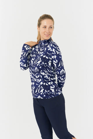 The Pure Golf Serenity long-sleeve ladies' golf zip top side view model shot showcasing our botanical print in Wild Peony Navy. Designed with a regular fit, it offers a 4-way stretch for comfort and a flattering shape on all body types. The mock neck collar offers a sleek, modern look and extra coverage. Made from 95% Polyester and 5% Spandex, offering anti-crease, anti-static, and quick-dry properties, along with UPF 50+ sun protection. Paired with Navy Bermuda Shorts. 