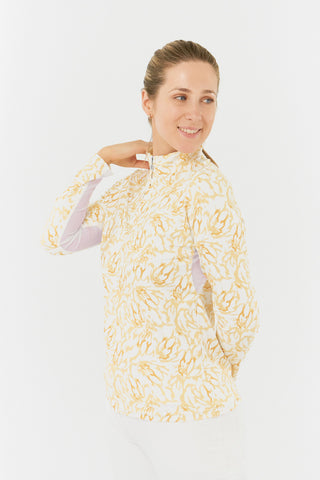 A close-up model shot of the Pure Golf Balance Sun Kissed Long Sleeve Ladies' Golf Zip Top from our Ray Flower collection shows a beautiful print in warm honey hues. With a regular fit and 4-way stretch, it ensures comfort for all body types. The mock neck collar adds a sleek touch, while mesh sleeve white panels enhance breathability. Crafted from 95% polyester and 5% spandex, it offers anti-crease, anti-static, and quick-dry properties, along with UPF 50+ protection. 