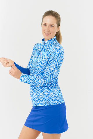 The close-up side model shot in the Pure Golf Balance Santorini Skies Long Sleeve Ladies' Golf Zip Top features a mesmerizing Ikat-inspired design in shades of blue and white. With a regular fit and 4-way stretch, it provides comfort for all body types. The sleek mock neck collar adds style, and the mesh inside sleeve and underarm panels in Royal Blue enhance breathability. Crafted from 95% polyester and 5% spandex, it offers anti-crease, anti-static, and quick-dry properties, along with UPF 50+.