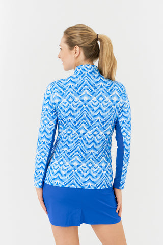 The close-up back model shot in the Pure Golf Balance Santorini Skies Long Sleeve Ladies' Golf Zip Top features a mesmerizing Ikat-inspired design in shades of blue and white. Regular fit and 4-way stretch, it provides comfort for all body types. The sleek mock neck collar adds style, and the mesh inside sleeve and underarm panels in Royal Blue enhance breathability. Crafted from 95% polyester and 5% spandex, it offers anti-crease, anti-static, and quick-dry properties, along with UPF 50+.