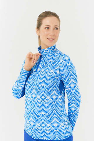 The side model shot of the Pure Golf Balance Santorini Skies Long Sleeve Ladies' Golf Zip Top highlights a mesmerizing Ikat-inspired design in shades of blue and white. With a regular fit and 4-way stretch, it provides comfort for all body types. The sleek mock neck collar adds a stylish touch, while the mesh inside sleeve and underarm panels in Royal Blue enhance breathability. Crafted from 95% polyester and 5% spandex, it offers anti-crease, anti-static, and quick-dry properties, along with UPF 50+. 