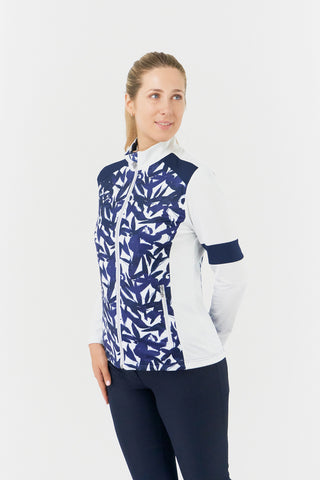 The Pure Golf Galena model shot highlights the side of the mid-layer jacket in Wild Peony, featuring a botanical navy and white print on the body and inner neck, white sleeves, a navy band around the elbow, and a navy block across the shoulders. Designed for comfort and a flattering fit, the jacket offers 4-way stretch to suit all body types. It is anti-crease, anti-static, quick-drying, and provides UPF 50+ sun protection. Made from 95% Polyester and 5% Spandex. 