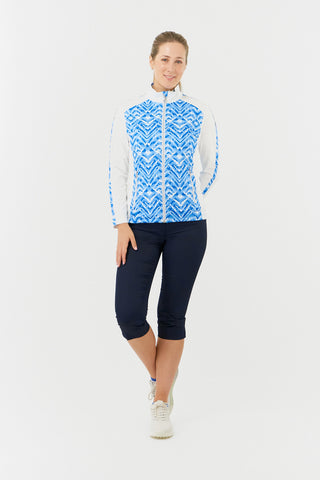 The front model shot of the Pure Golf Gia Mid Layer Jacket in Santorini Skies showcases its striking Ikat-inspired blue print, elegantly placed inside the mock collar and across the main body, with a slim seam running from the shoulders down the sleeves. Featuring 4-way stretch, the jacket ensures a flattering fit on all body types. It’s designed with anti-crease, anti-static, and quick-drying properties, along with UPF 50+. Made from 95% Polyester and 5% Spandex. Paired with Navy Trust Capri's.