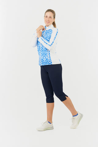 The side model shot of the Pure Golf Gia Mid Layer Jacket in Santorini Skies highlights its striking Ikat-inspired blue print, beautifully placed inside the mock collar and across the main body, with a slim seam running from the shoulders down the sleeves. With 4-way stretch, the jacket offers a flattering fit for all body types. It’s crafted with anti-crease, anti-static, and quick-drying properties, as well as UPF 50+ sun protection. Made from 95% Polyester and 5% Spandex, Paired with Navy Trust Capri's.