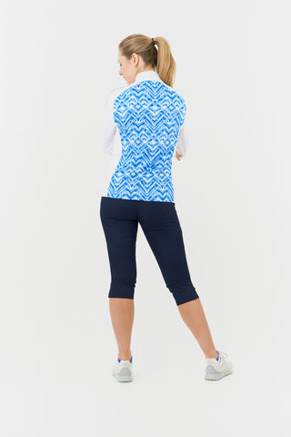 The back model shot of the Pure Golf Gia Mid Layer Jacket in Santorini Skies showcases its bold Ikat-inspired blue print, elegantly placed inside the mock collar and across the main body, with a slim seam running from the shoulders down the sleeves. Featuring 4-way stretch, the jacket ensures a flattering fit for all body types. Designed with anti-crease, anti-static, and quick-drying properties, along with UPF 50+ sun protection, it combines performance with style. Made from 95% Polyester and 5% Spandex. 