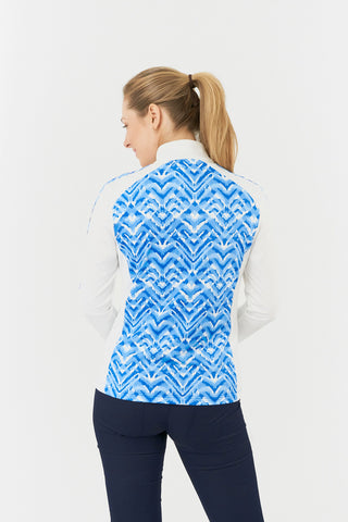 The close up back model shot of the Pure Golf Gia Mid Layer Jacket in Santorini Skies showcases its bold Ikat-inspired blue print, elegantly placed inside the mock collar and across the main body, with a slim seam running from the shoulders down the sleeves. Featuring 4-way stretch, the jacket ensures a flattering fit for all body types. Designed with anti-crease, anti-static, and quick-drying properties, along with UPF 50+, it combines performance with style. Made from 95% Polyester and 5% Spandex. 