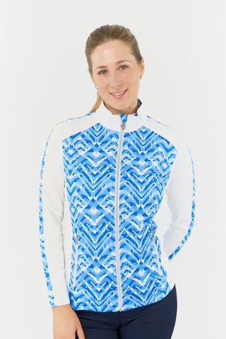 The close-up model shot of the Pure Golf Gia Mid Layer Jacket in Santorini Skies highlights its striking Ikat-inspired blue print, beautifully placed inside the mock collar and across the main body, with a slim seam running from the shoulders down the sleeves. The 4-way stretch ensures a flattering fit for all body types, while its anti-crease, anti-static, and quick-drying properties, along with UPF 50+ sun protection, make it both practical and stylish. Made from 95% Polyester and 5% Spandex. 